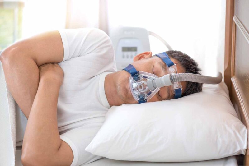 Man slaapt op zijn zij met een CPAP-masker op